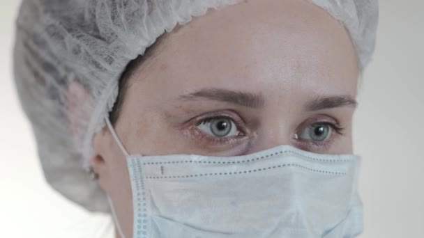 Close up of a female nurse putting on a respirator N95 mask to protect from airborne respiratory diseases such as the flu, coronavirus, ebola, TB, etc - Кадри, відео