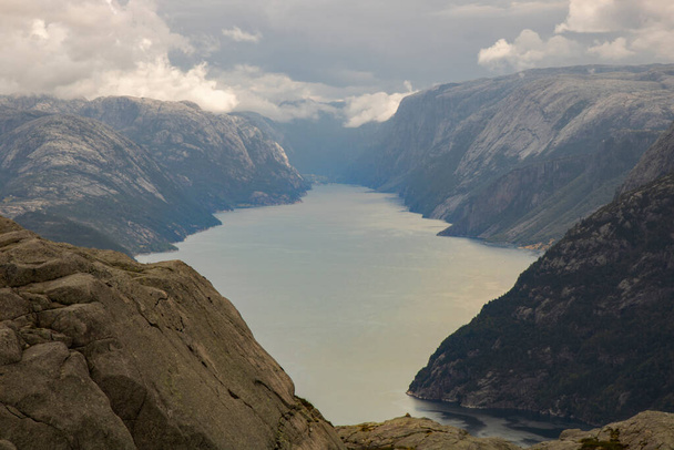 Increíble paisaje que muestra Lysefjord y algunas montañas alrededor bajo un cielo nublado en la ruta de trekking a Preikestolen púlpito turístico roca
 - Foto, imagen