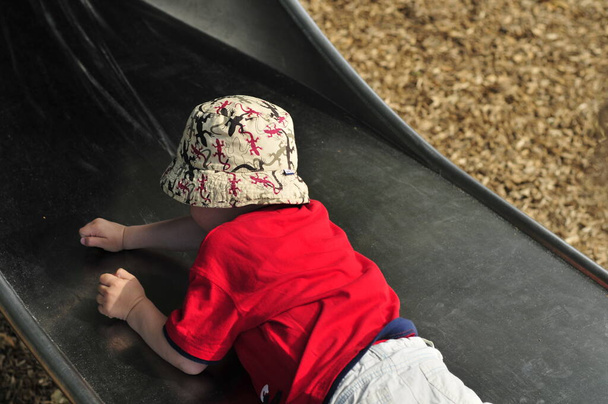 Παιδί ανάποδα στην τσουλήθρα σε μια παιδική χαρά - Φωτογραφία, εικόνα