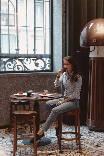 Girl in a beautiful trendy cafe. Girl at the table with a cup of coffee. - Foto, Imagen