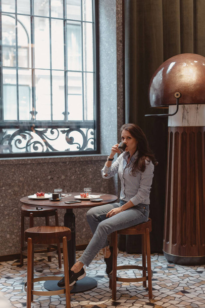 Young beautiful girl in a beautiful trendy cafe at the table. - Zdjęcie, obraz