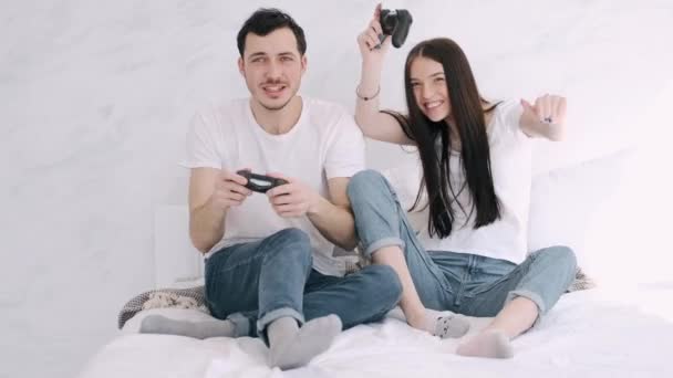Pretty girl and boyfriend are playing play station in bed - Filmmaterial, Video
