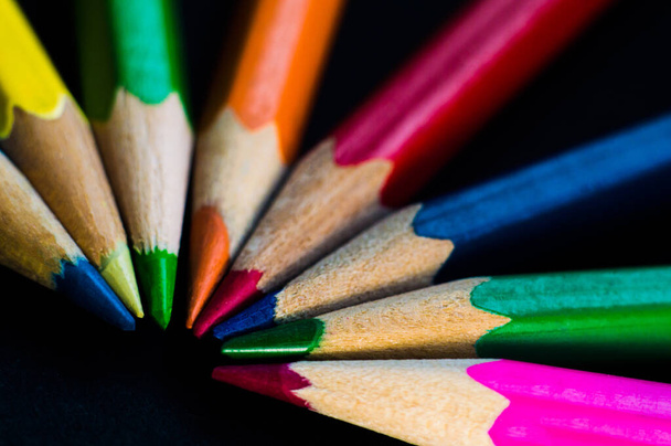 Pencils in different colors on black background. Pencils closeup in bokeh. Postcard or wallpaper - Foto, imagen