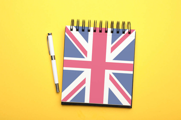 Stylish notebook and pen on yellow background, top view. Learning English - Foto, Bild