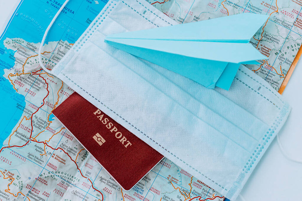 Blue paper airplane,passport and protective mask on the background of a map of Greece.Concept of a flight ban due to coronavirus pandemic. - Foto, afbeelding