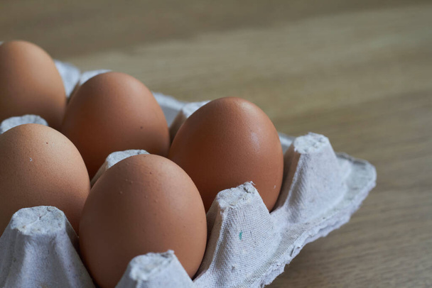 Hnědá vejce detailní záběr, kuřecí vejce v kartonovém podnosu na dřevěném stole, selektivní zaměření - Fotografie, Obrázek