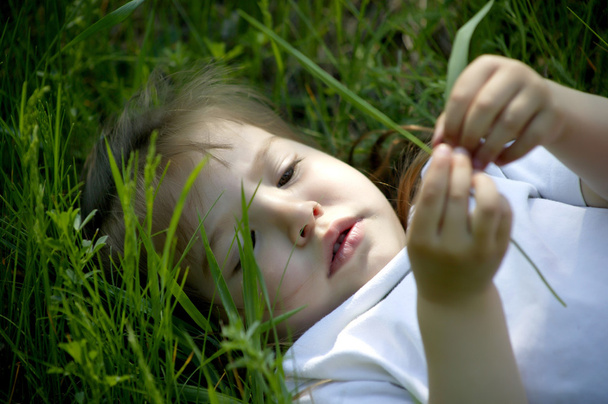 Belle petite fille pose sur l'herbe verte
 - Photo, image