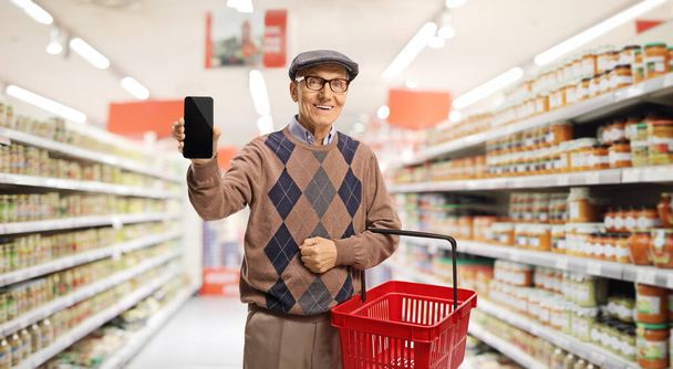 Homme âgé avec un panier dans un supermarché montrant pouces vers le haut
 - Photo, image