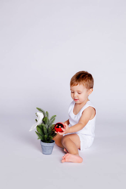 ребенок пытается украсить елку рождественской игрушкой
 - Фото, изображение