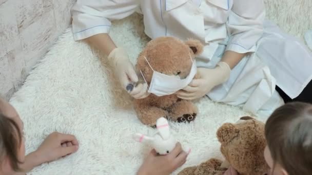 Çocuklar hastanede oynuyor. Çocuklar tıbbi koruyucu maskeli oyuncak ayılarla oynarlar. Oyun doktor, hemşire, veteriner gibi davranır. Hastayı aşıyla tedavi eder. Koronavirüs tehlikesi. - Video, Çekim