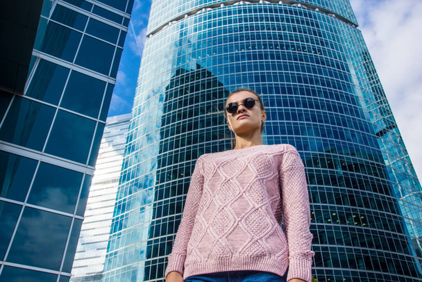 junge Frau vor dem Hintergrund eines hohen Firmengebäudes - Foto, Bild