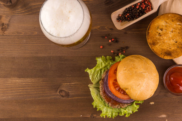 Kotitekoinen hampurilainen ja lasi olutta tumman maalaismainen puinen tausta kopioi tilaa
 - Valokuva, kuva