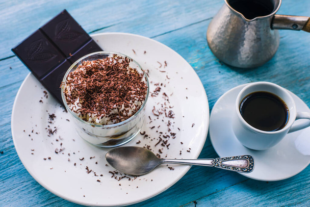 自家製のイタリアのデザートティラミスには、すりおろしたチョコレートと素朴なテーブルの上のコーヒーカップがあります。 - 写真・画像