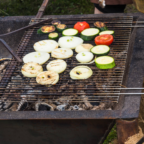 Street food - Vegetables zucchini, onions and tomatoes are roasted on the grill - Photo, Image