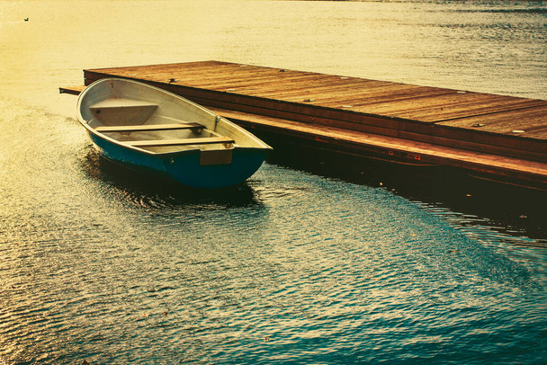 Un bateau attaché à une jetée en bois sur le lac le soir au coucher du soleil
 - Photo, image