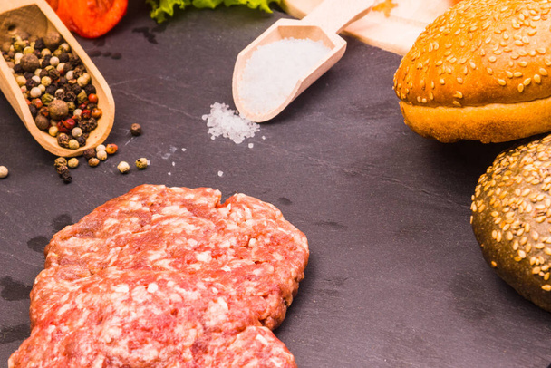 Raw burgers, buns, salad with tomatoes and ingredients for homemade hamburger - Foto, Imagem