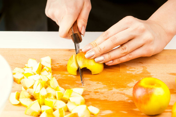 Le mani femminili tagliano una mela in pezzi primo piano per una torta di mele
 - Foto, immagini