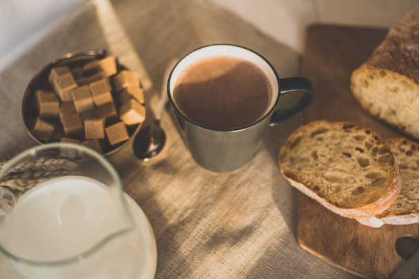 Горщик гарячого шоколаду, молока та хліба на дерев'яному фоні рано вранці
 - Фото, зображення