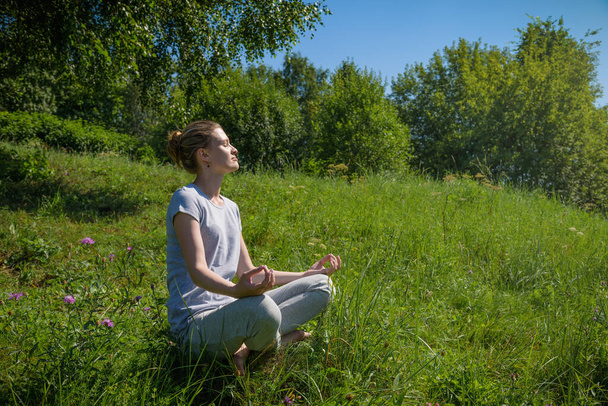 Giovane donna attraente meditando in posizione loto all'aperto
 - Foto, immagini