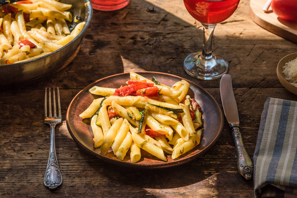 Hagyományos olasz rusztikus ebéd - tészta penne grillezett cukkinivel és paradicsommal és egy pohár házi borral - Fotó, kép