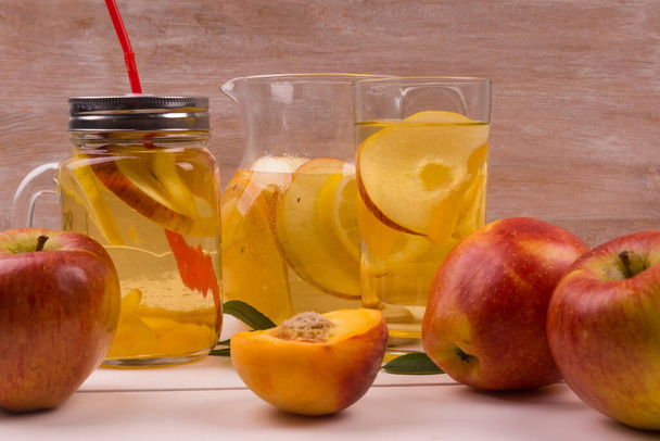 Orzeźwiający zimny detoks z jabłek, brzoskwiń i owoców cytrusowych w szklance na stole z owocami - Zdjęcie, obraz