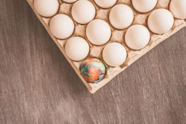 Colorful eggs and a cardboard box with white eggs - Photo, Image