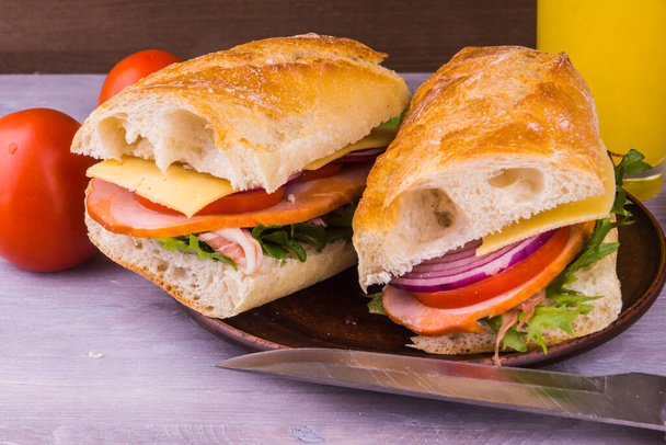 ハム、チーズ、レタス、玉ねぎとトマトの素朴な木製の背景に潜水艦サンドイッチ - 写真・画像