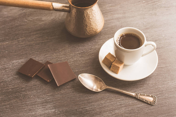 Eine Tasse Kaffee auf dem Tisch, türkische Kaffeekanne und Schokolade - Foto, Bild