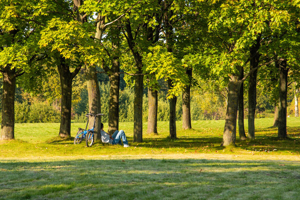 Moscú, Rusia, 7 de septiembre de 2019 - Un hombre está descansando en un parque debajo de un árbol, poniendo su bicicleta al lado
 - Foto, imagen