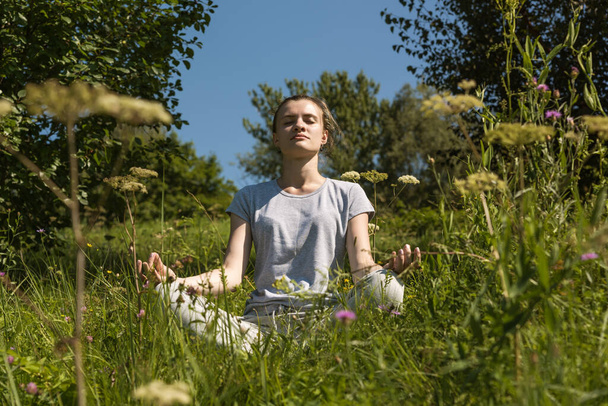 Junge attraktive Frau meditiert in Lotusposition im Freien - Foto, Bild