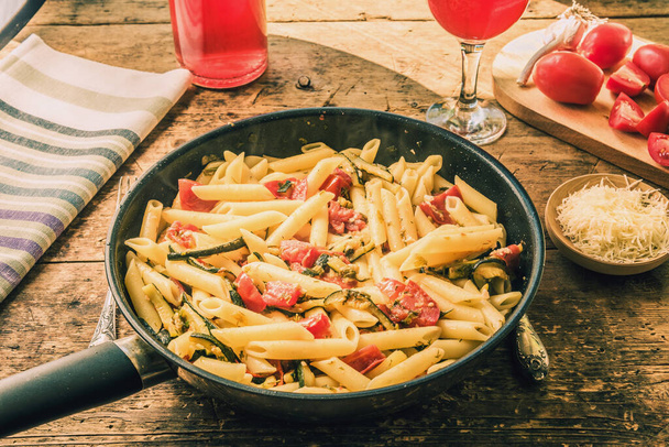 Perinteinen kasvissyöjä italialainen pasta kesäkurpitsan ja tomaattien kanssa paistinpannulla
 - Valokuva, kuva