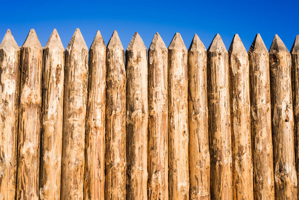 Деревянный забор из обостренных плановых бревен
 - Фото, изображение