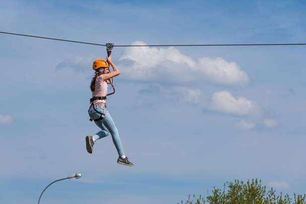Russia, Moscow, Kolomenskoye Park, May 2, 2018 - Girl riding on a zip line against a blue sky - Photo, Image
