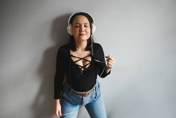 Young woman enjoys music in white headphones at home - Foto, afbeelding