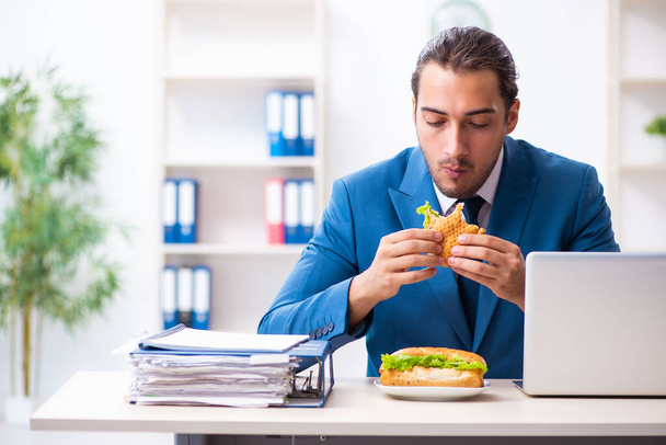 Young male employee having breakfast at workplace - Foto, immagini