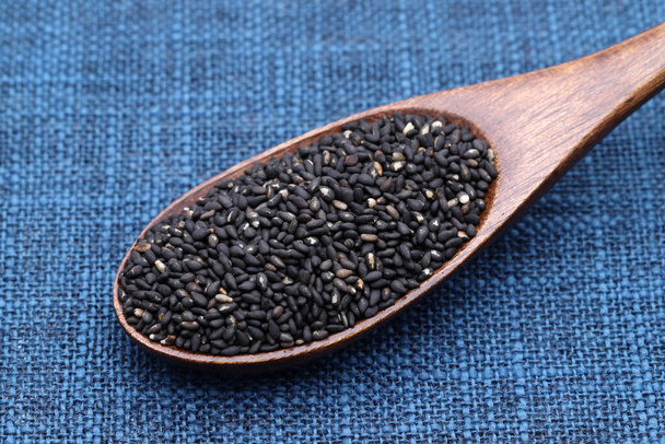 czarne nasiona sezamu w drewnianej łyżce na stole  - Zdjęcie, obraz