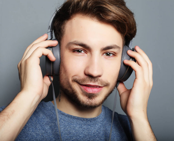 Handsome young man wearing headphones and listening to music. - Фото, изображение