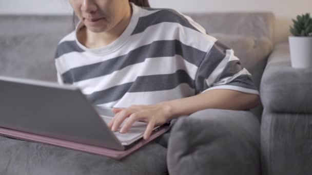 4K junge asiatische Frau arbeitet mit Laptop zu Hause. Arbeit auf der Couch zu Hause, konzentrierte sich auf freiberufliche Arbeit, Homeoffice-Arbeit. Selbst Quarantäne covid-19, asiatische College-Student E-Mail-Chat mit Freunden - Filmmaterial, Video