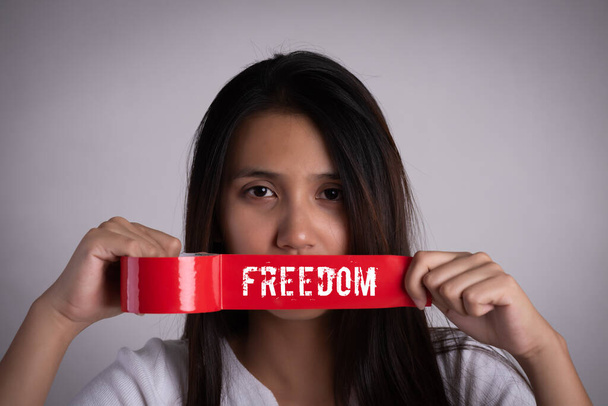Молодая женщина заворачивала свое крепление клейкой лентой, концепцией свободы слова, цензуры, свободы прессы. Международный день прав человека
. - Фото, изображение
