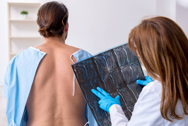 Nuori selkä loukkaantunut mies vierailevat naislääkärin kiropraktikko
 - Valokuva, kuva