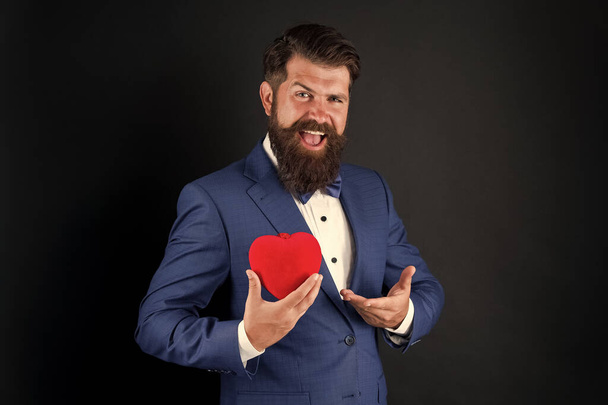 It is perfect. Valentines day decoration. tuxedo man with red heart. Holiday celebration. love concept. World heart day. brutal bearded hipster in formal suit. businessman in bow tie. Health care - Photo, Image