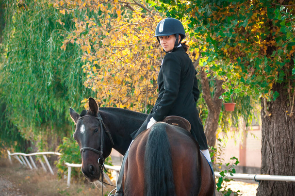 hermosa sonriente chica jockey stand al lado de su marrón caballo usando especial
 - Foto, Imagen