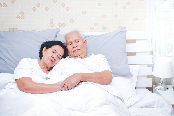Ασιάτες ηλικιωμένοι κοιμούνται στο κρεβάτι στην κρεβατοκάμαρα. Ανώτερες έννοιες υγείας, ασθένεια, συνταξιοδότηση. αντίγραφο χώρου - Φωτογραφία, εικόνα
