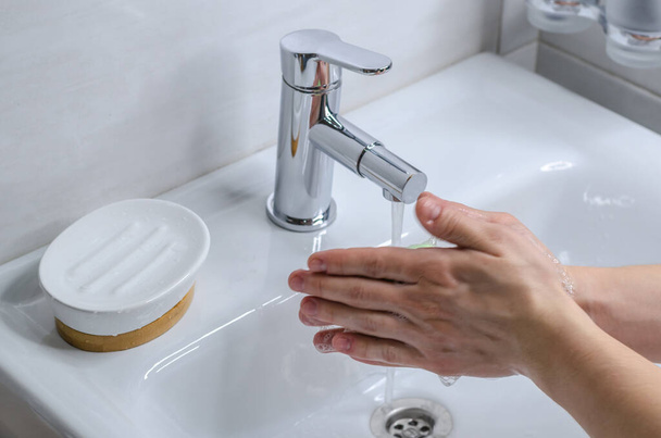 Hand washing with soap. Preventive measures against infection. A young guy washes his hands with soap in the bathroom. Body hygiene. The fight against COVID-19 - Foto, Bild