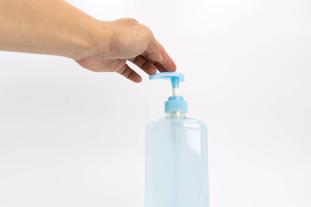 Mand main asiatique tient une bouteille de pompe à alcool gel et prêt à pousser sur elle. C'est un objet isolé sur l'écran blanc clair dans la lumière du studio.. - Photo, image