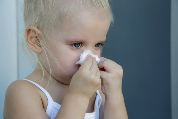 Nahaufnahme freimütiges Porträt eines kleinen Mädchens, das die Nase pustet. Schnupfen durch Erkältung, Grippe oder Allergie. - Foto, Bild