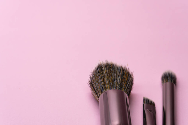 コピースペースとピンクの背景に銀ハンドル付きのプロの化粧ブラシ。美しさと顔の化粧品のコンセプト - 写真・画像