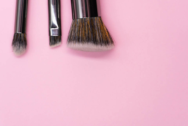 Professionelle Make-up-Pinsel mit silbernem Griff auf rosa Hintergrund mit Kopierraum. Konzept für Schönheit und Gesichtskosmetik - Foto, Bild