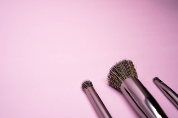コピースペースとピンクの背景に銀ハンドル付きのプロの化粧ブラシ。美しさと顔の化粧品のコンセプト - 写真・画像
