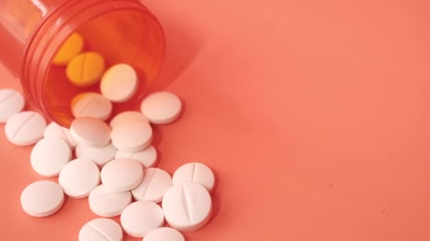 bílé pilulky a oranžové kontejner na barevném pozadí  - Záběry, video